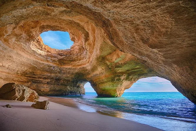 Морская пещера в Алгарве, Португалия   одно из самых популярных мест у туристов. Её отличают два выхода и отверстие в потолке, тогда как дно пещеры покрыто мелким пляжным песком.  