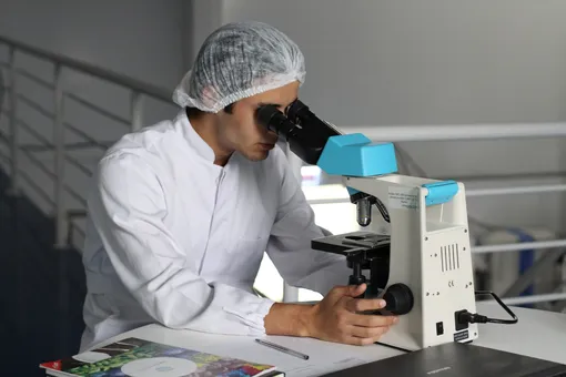 Медицинский работник сидит за микроскопом