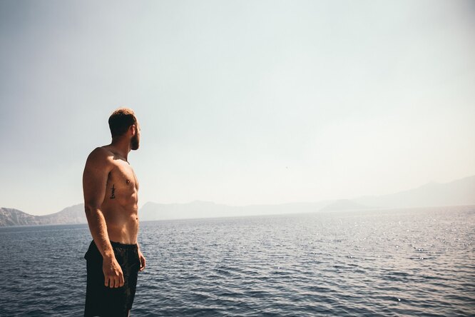 Стройный мужчина у моря смотрит вдаль: похудение для мужчины полезно