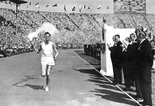 Представители Международного олимпийского комитета приветствуют факелоносца на церемонии открытия Олимпийских игр1948 года в Лондоне. Официальный девиз МОК «Быстрее, выше, сильнее» был изменен 20 июля 2021 года на «Быстрее, выше, сильнее — вместе».