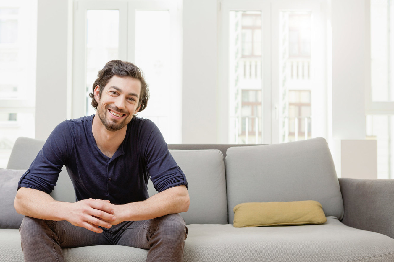 Man sitting on Sofa with Phone. Man sitting in Romm. Man sitting on Sofa.