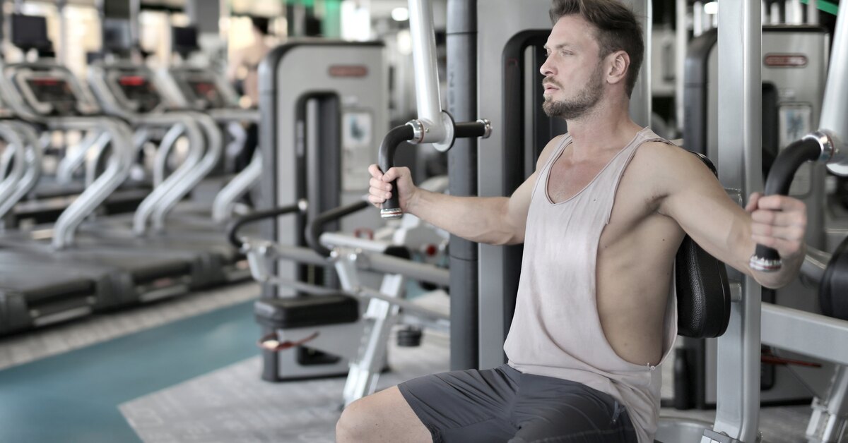 Тренировка знаний. Тренажер Атлет. Мужчина на тренажере в светлых тонах. Тренажерный зал сейчас. Чужой в спортзале.